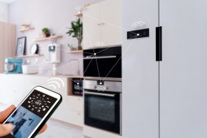 Smart home concept with hand holding cell phone controlling appliances in kitchen